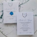 invitație de nuntă bleu albastră cu monogramă florală și sigiliu de ceară